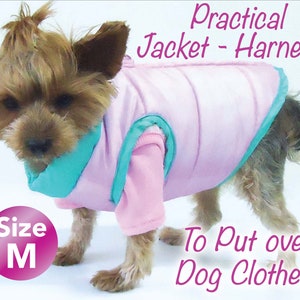 May include: A small dog wearing a pink and teal jacket-harness. The jacket is designed to be put over dog clothes. The text on the image reads "Practical Jacket - Harness" and "To Put over Dog Clothes". The size is marked as "M".