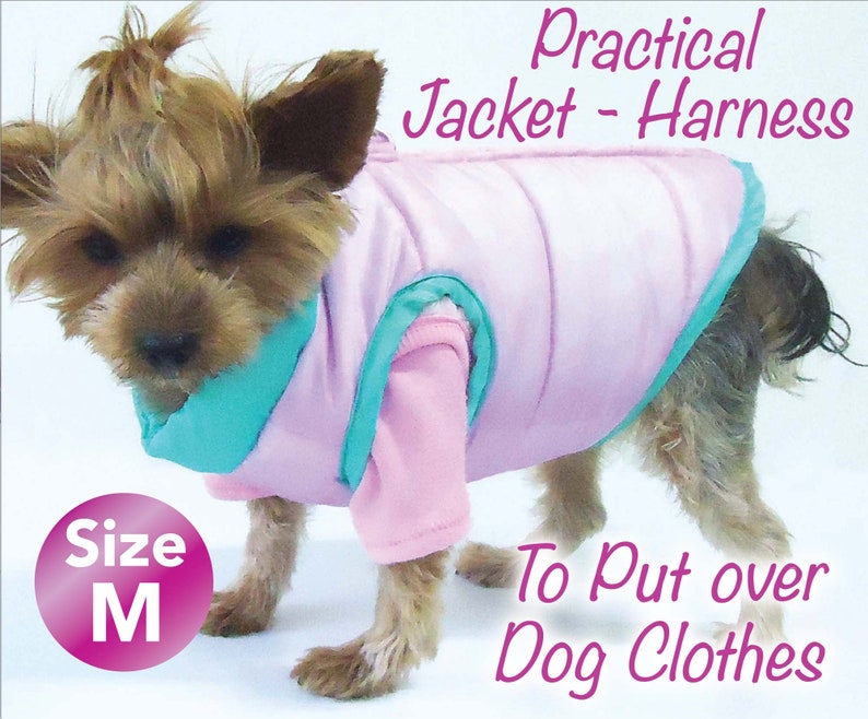 May include: A small dog wearing a pink and teal jacket-harness. The jacket is designed to be put over dog clothes. The text on the image reads "Practical Jacket - Harness" and "To Put over Dog Clothes". The size is marked as "M".