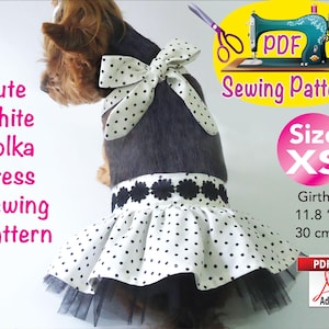 Puede incluir: Un perro con un vestido blanco de lunares con una falda de tul negra y un lazo a juego. El vestido es un patrón de costura, talla XS, con un contorno de 30 cm (11,8 pulgadas). La imagen incluye el texto "Cute White Polka Dress Sewing Pattern".