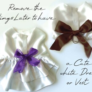 Puede incluir: Dos conjuntos blancos de sat&eacute;n para mascotas, uno con un lazo morado y otro con un lazo marr&oacute;n. El texto dice: "Remove the Wings Later to have a Cute white Dress or Vest."