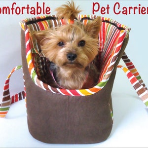May include: A brown and striped pet carrier with a small dog inside. The carrier has a comfortable design and is perfect for taking your pet on the go. The text "Comfortable Pet Carrier" is written above the carrier.