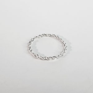Könnte beinhalten: Ein silberner Ring mit geflochtenem Design.