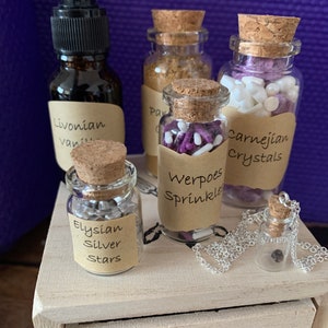 Puede incluir: Una caja de madera con cinco peque&ntilde;os frascos de vidrio que contienen varios art&iacute;culos. Los frascos tienen tapones de corcho y etiquetas con nombres como "Livonian Vanilla", "Werpoes Sprinkles", "Elysian Silver Stars" y "Carnelian Crystals".