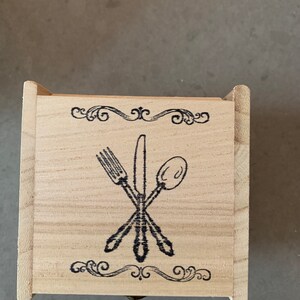 Puede incluir: Una caja de madera con un dise&ntilde;o decorativo de un tenedor, cuchillo y cuchara. La caja tiene un acabado de madera clara y un dise&ntilde;o negro.