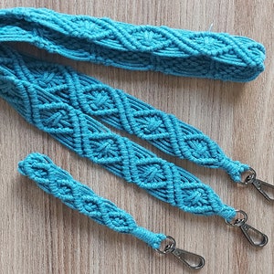 May include: A turquoise blue macrame strap with two silver clasps. The strap is made of a thick, woven cord and has a diamond pattern.