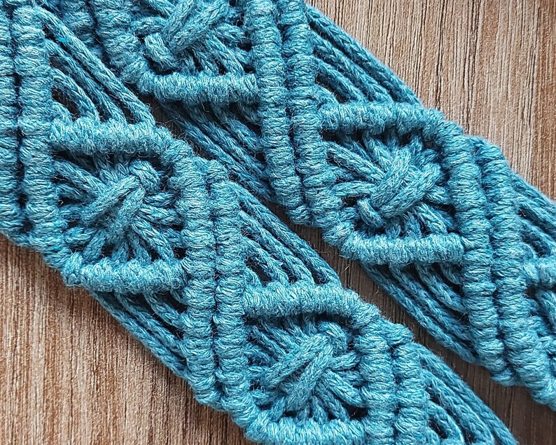 May include: A close-up of a teal blue macrame cord with a diamond pattern. The cord is woven into a decorative design.