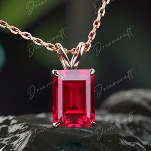 Peut inclure: Un collier en chaîne en or rose avec un pendentif orné d'une grande pierre précieuse de rubis taille émeraude.