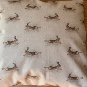 May include: A beige throw pillow with a repeating pattern of brown rabbits running across the fabric.