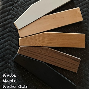 May include: Five wood samples in different colors: white, maple, white oak, walnut, and black. The samples are arranged in a fan shape, with the white sample at the top and the black sample at the bottom.