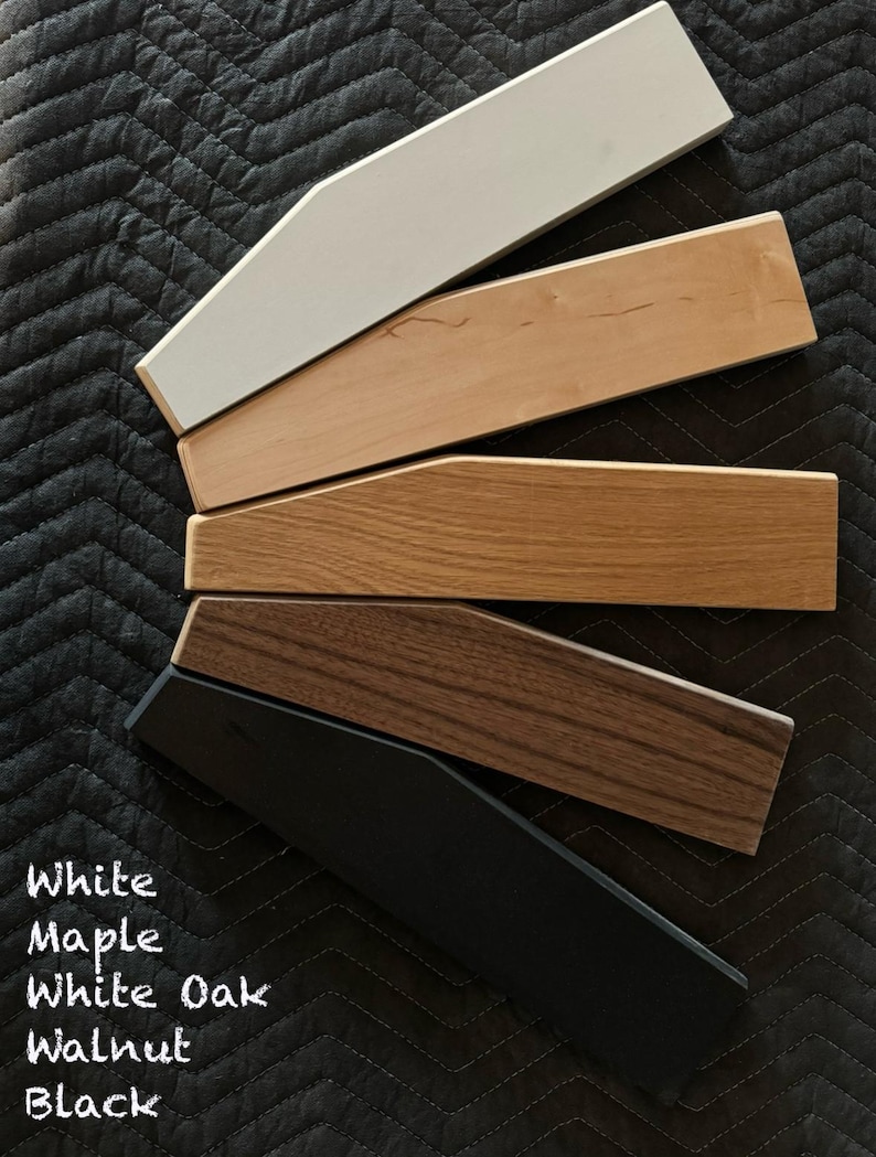 May include: Five wood samples in different colors: white, maple, white oak, walnut, and black. The samples are arranged in a fan shape, with the white sample at the top and the black sample at the bottom.