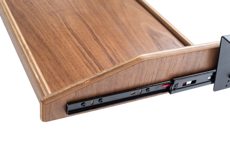 May include: Close-up of a wooden drawer slide with black metal rails and a red plastic release button. The drawer slide is attached to a wooden drawer with a beveled edge.