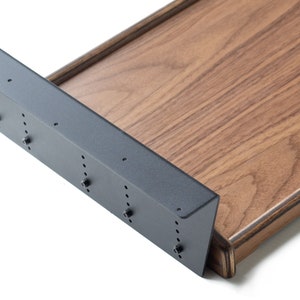 May include: A close-up of a wooden shelf bracket with a black metal support. The bracket is attached to a wooden shelf with screws. The shelf is made of a dark wood with a natural grain.