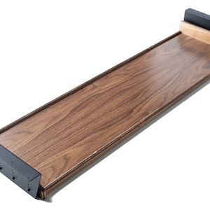 May include: A wooden shelf with black metal brackets. The shelf is made of walnut wood and has a natural finish.