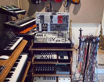 Puede incluir: Una configuración de estudio de música con una variedad de instrumentos electrónicos, que incluyen un sintetizador, un teclado y una caja de ritmos. También hay varias guitarras colgadas en la pared.