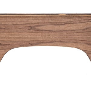 May include: A wooden shelf with a curved cutout in the front. The shelf is made of dark wood with a natural grain pattern. The shelf has black metal brackets on either side.