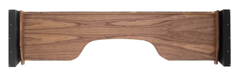 May include: A wooden shelf with a curved cutout in the front. The shelf is made of dark wood with a natural grain pattern. The shelf has black metal brackets on either side.