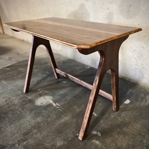 May include: A wooden desk with a light brown top and dark brown legs. The desk has a simple, modern design and is made of high-quality wood.