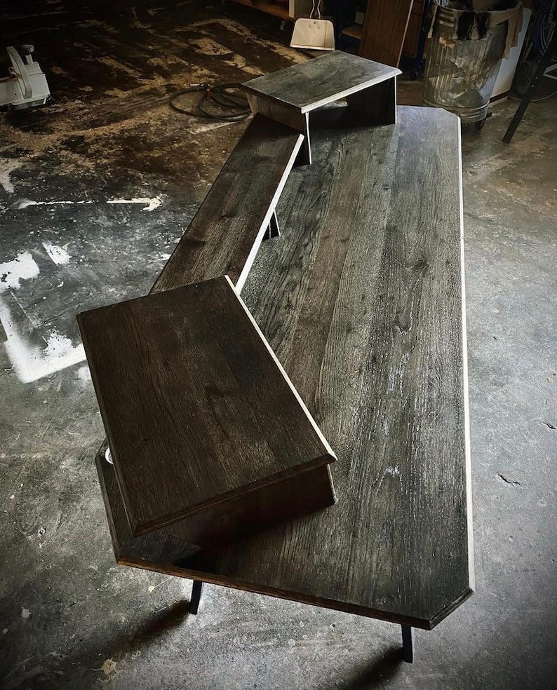 May include: A dark wood desk with three shelves. The desk has a rustic finish and is supported by black metal legs.