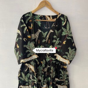 May include: Black dress with a jungle animal print featuring zebras, leopards, and birds among green foliage. The dress has a V-neck and three-quarter sleeves. The text "Mycraftsvilla" is visible on the dress.