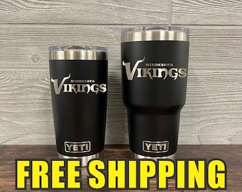 May include: Two black Yeti tumblers with stainless steel lids and bases. The tumblers are engraved with the words "Minnesota Vikings" and "YETI".