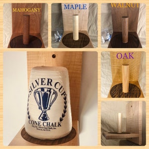 May include: A wooden wall mount for holding a cone of chalk. The mount is available in five different wood types: mahogany, maple, walnut, oak, and cherry. The mount features a round base and a cylindrical post for holding the chalk. The chalk is labeled "Silver Cup Cone Chalk" and is made in the USA.