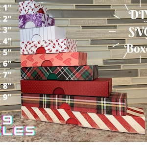 May include: Nine DIY SVG box files for creating small boxes in various sizes, ranging from 2 inches by 1 inch to 2 inches by 9 inches. The boxes are stacked in a pyramid shape and feature different festive patterns, including plaid, candy canes and hearts.