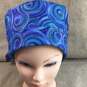 Könnte beinhalten: Eine blaue und violette gemusterte OP-Haube mit einem wirbelnden Design.