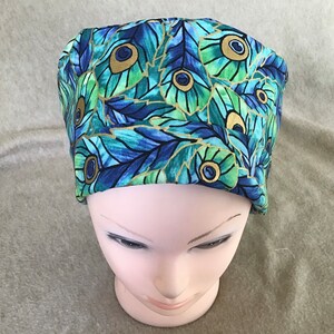 May include: A blue and green scrub hat with a peacock feather pattern. The hat has gold accents and is made of a soft, comfortable fabric.