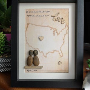 May include: Framed artwork with a black frame, featuring a map of the United States. The artwork includes the text "Our Cross-Country Adventure 2021" and "13,425 miles; 89 days; 36 states." A wooden "love" and two heart accents are also included.