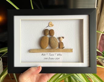 May include: Framed pebble art featuring a couple and a dog, with a heart-shaped balloon that says "Love". The artwork includes the names "Make ❤️ Tenicia ❤️ Wilson" and the date "25th October 2024". The frame is black.