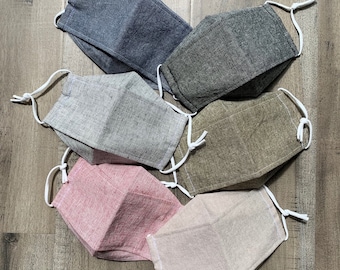 May include: Six fabric face masks in various colors and patterns, including gray, brown, beige, and pink. The masks are made of a soft, breathable material and have adjustable ear loops.