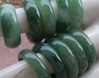 May include: A stack of jade rings in various shades of green. The rings are smooth and polished, with a glossy finish.