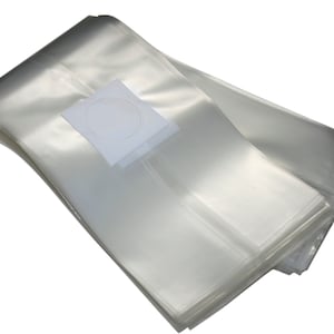 May include: A stack of clear, transparent plastic bags, likely for packaging or storage. A white label with a circular design is visible on top of the bags. The bags are folded and appear to be sealed.