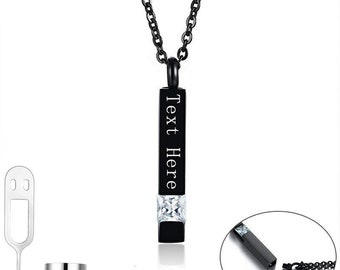 May include: A black vertical bar pendant necklace featuring a clear square-cut gemstone and the text "Text Here" engraved on the front. The set includes a small silver-toned funnel and a metal tool for filling the pendant, plus a circular inset showing the pendant detached from the chain.