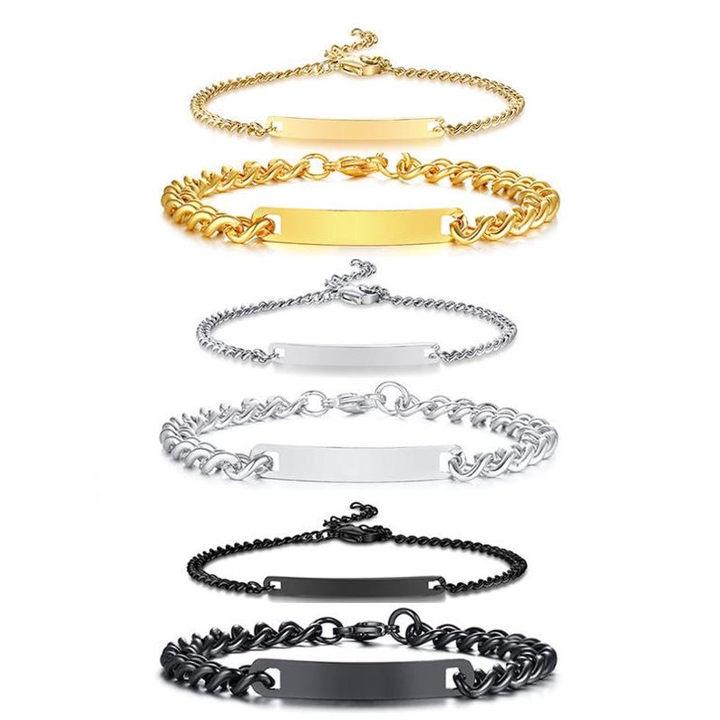 May include: A collection of six metal bracelets arranged in pairs. Each pair includes one thin chain and one thicker curb chain, each featuring a central rectangular identification plate. The set includes gold, silver, and black colored metal finishes.