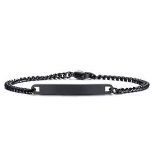May include: A matte black metal ID bracelet featuring a flat, rectangular identification plate centered on a delicate curb chain. The bracelet is secured with a matching black lobster claw clasp, presenting a uniform dark finish throughout the design.