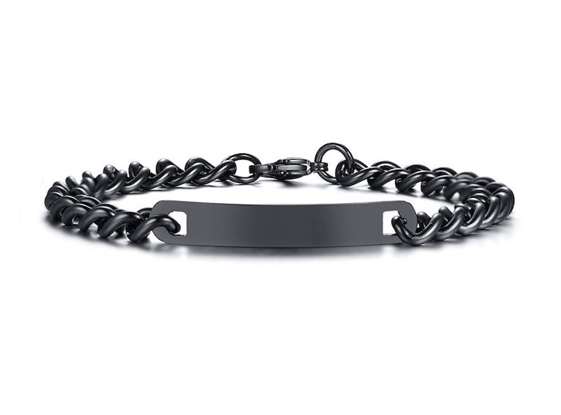May include: A matte black metal chain bracelet featuring a smooth, rectangular identification plate at the center. The bracelet is constructed with interlocking curb links and includes a secure lobster claw clasp closure at the back.