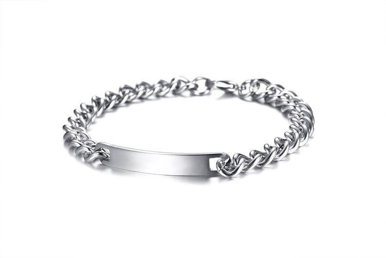 May include: A silver-toned metal chain bracelet featuring a smooth, rectangular identification plate at the center. The bracelet is constructed with interlocking curb links and includes a secure clasp mechanism visible at the back of the chain.