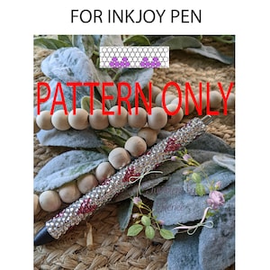 May include: A silver pen with red rhinestones, a heart pattern, and the text "PATTERN ONLY" in red letters. The pen is lying on a woven surface with wooden beads and a floral design.
