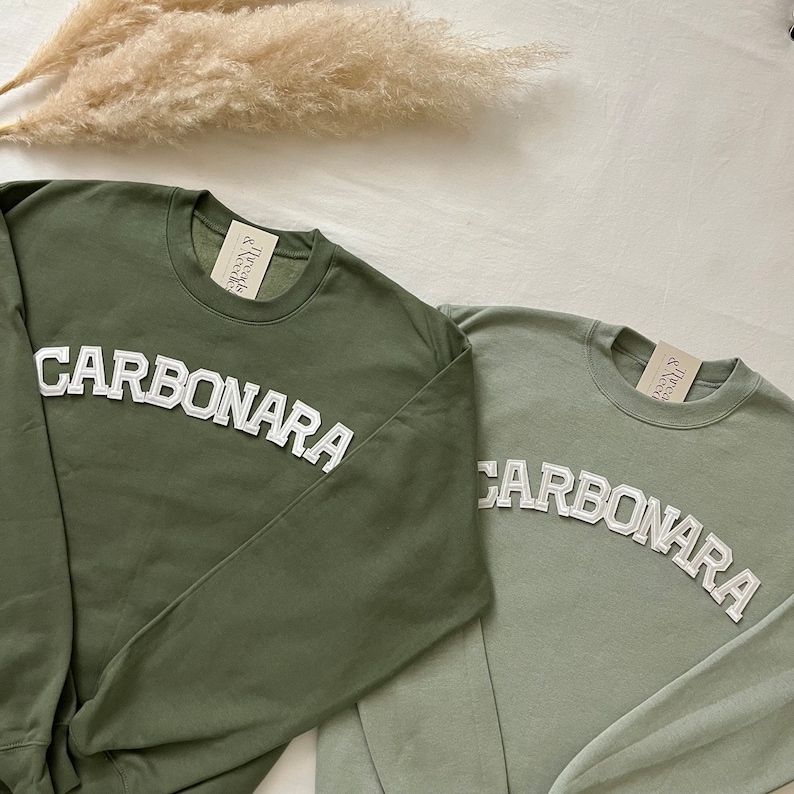 Puede incluir: Dos sudaderas verdes con la palabra "Carbonara" en letras blancas en la parte delantera. Las sudaderas est&aacute;n hechas de un material suave y c&oacute;modo y son perfectas para el uso diario.