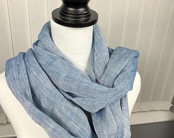 May include: A light blue scarf with a textured, slightly speckled appearance. The scarf is folded and draped over a mannequin's neck.