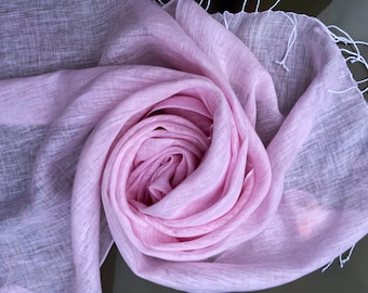 May include: A soft, pink linen scarf with a delicate fringe. The scarf is folded and arranged in a rose-like shape.