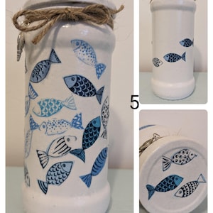 May include: White glass jar with a blue and white fish design. The jar has a brown twine bow around the top and a metal lid.
