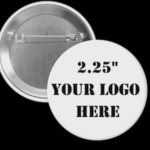 May include: A white, round button with a 2.25-inch diameter. The button features the text "YOUR LOGO HERE" in bold, black letters. The back of the button is silver with a pin for attachment. The button is against a black background.