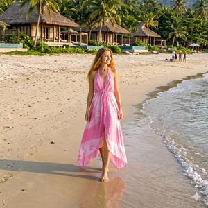 May include: A sleeveless maxi dress in a light pink hue featuring a white tie-dye circular pattern. The dress has a deep V-neckline, thin shoulder straps, and a drawstring waist tie that creates a gathered effect, with an asymmetrical hemline.