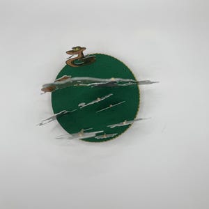 Peut inclure: Une carte pop-up 3D ronde en papier de couleur verte avec une bordure dor&eacute;e. La carte repr&eacute;sente un serpent avec une t&ecirc;te verte et une couronne dor&eacute;e. Le serpent est sur une base verte avec des nuages blancs.