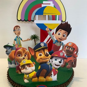 Puede incluir: Un adorno para pastel con tem&aacute;tica de la Patrulla Canina con los personajes Chase, Marshall, Skye, Rocky, Rubble y Ryder. El adorno incluye un arco&iacute;ris y un faro con una parte superior amarilla y azul.