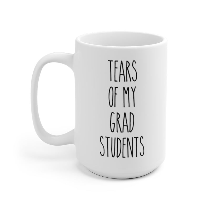 May include: White ceramic coffee mug with black text that reads "Tears of my grad students".