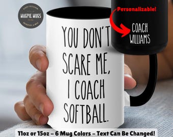 May include: White ceramic mug with a black interior and handle. The mug features the text "YOU DON'T SCARE ME, I COACH SOFTBALL" in black. A black mug with "COACH WILLIAMS" is also shown. The mug is available in 11oz or 15oz sizes.