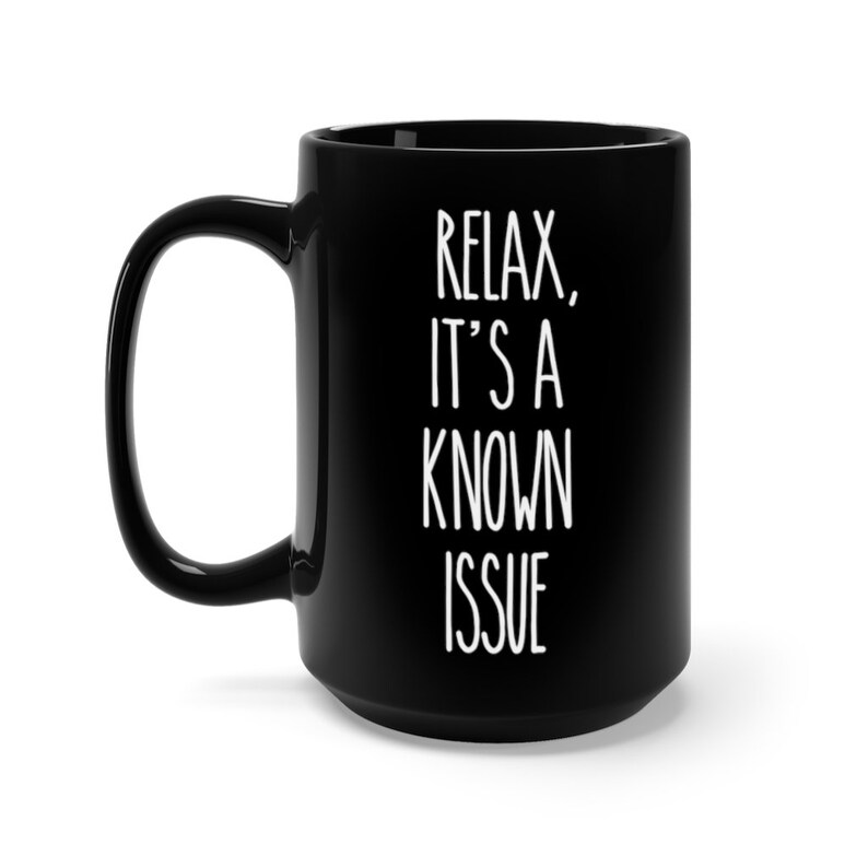 Puede incluir: Taza de caf&eacute; de cer&aacute;mica negra con texto blanco que dice "Rel&aacute;jate, es un problema conocido".